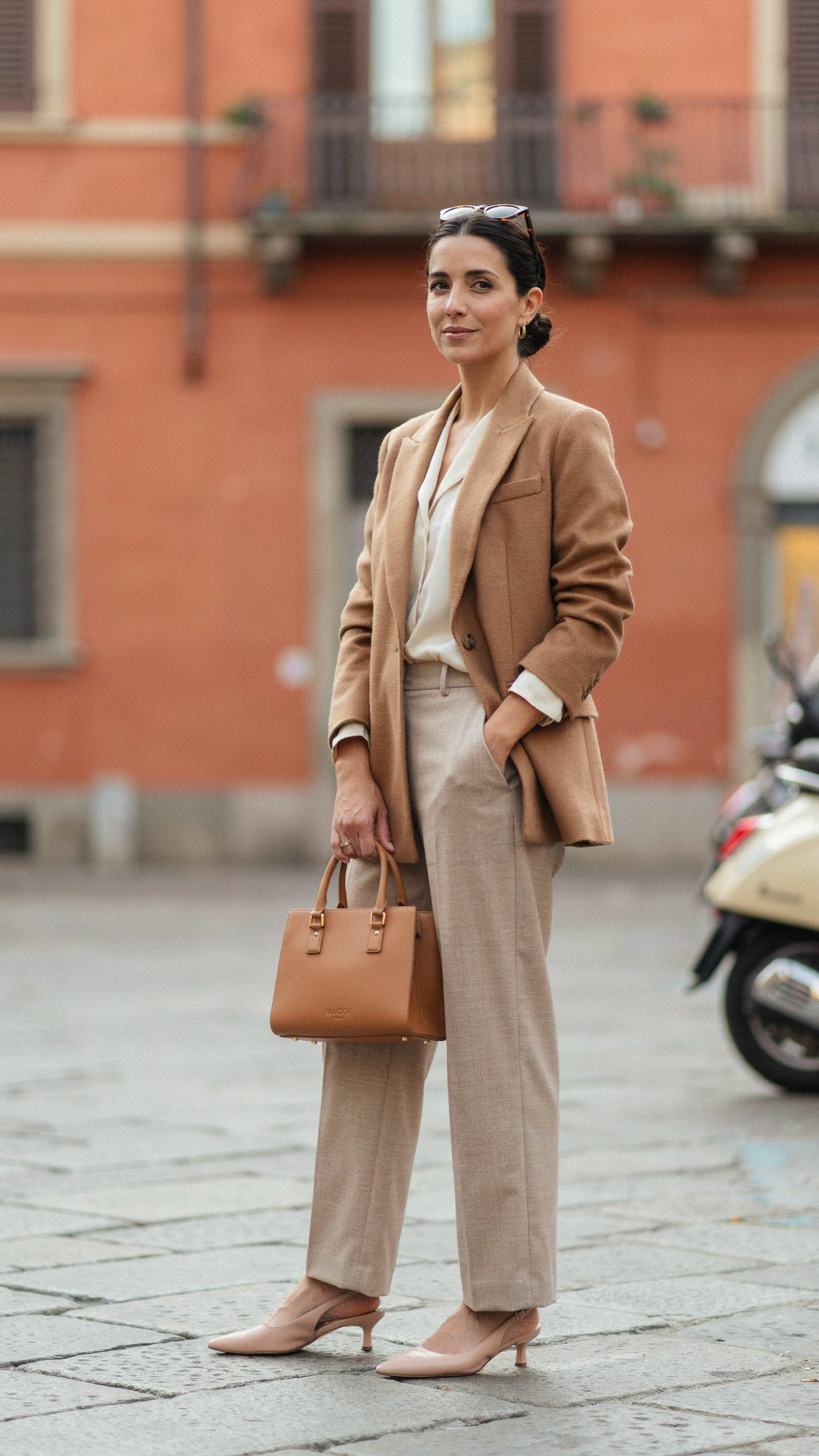 Elegant structured leather handbag styled with a tailored blazer, neutral trousers, and classic Italian inspired clothing.